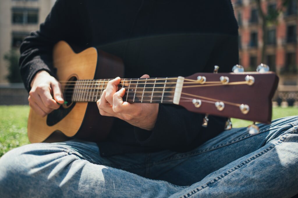 公園でギターを弾く男性の画像
